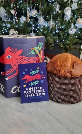 Confezione panettone decorata con disegni in viola e rosso e panettone intero su tavolo bianco 
